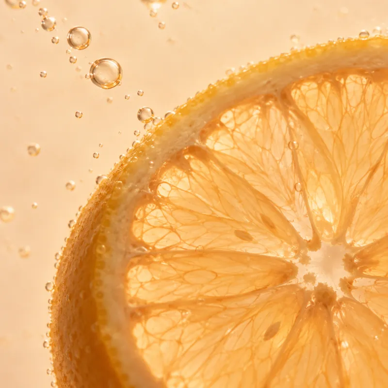 A cut lemon in clear liquid with bubbles rising beside it.