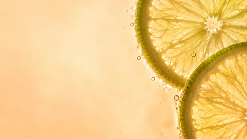 Backlit lime slices in clear water with tiny bubbles.