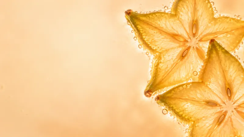 Star-shaped starfruit slices in clear water with bubbles.