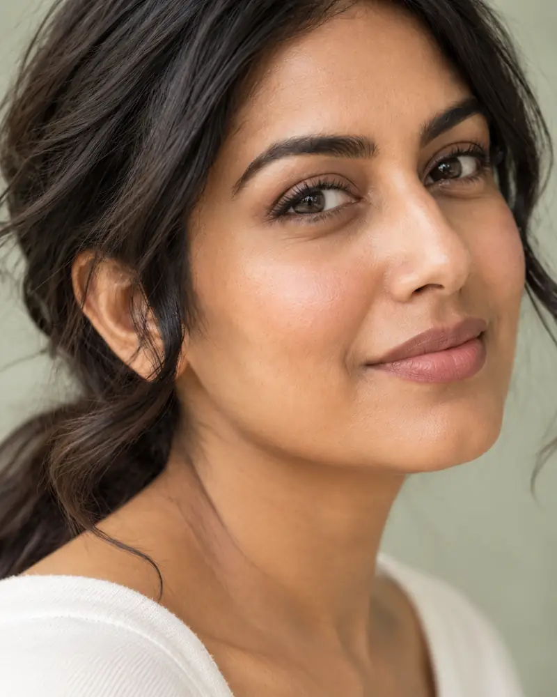 A woman with long dark hair, looking towards the camera in soft side light